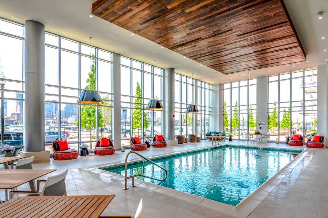 Pool area with giant glass walls, beautiful space with seating and tasteful design features.