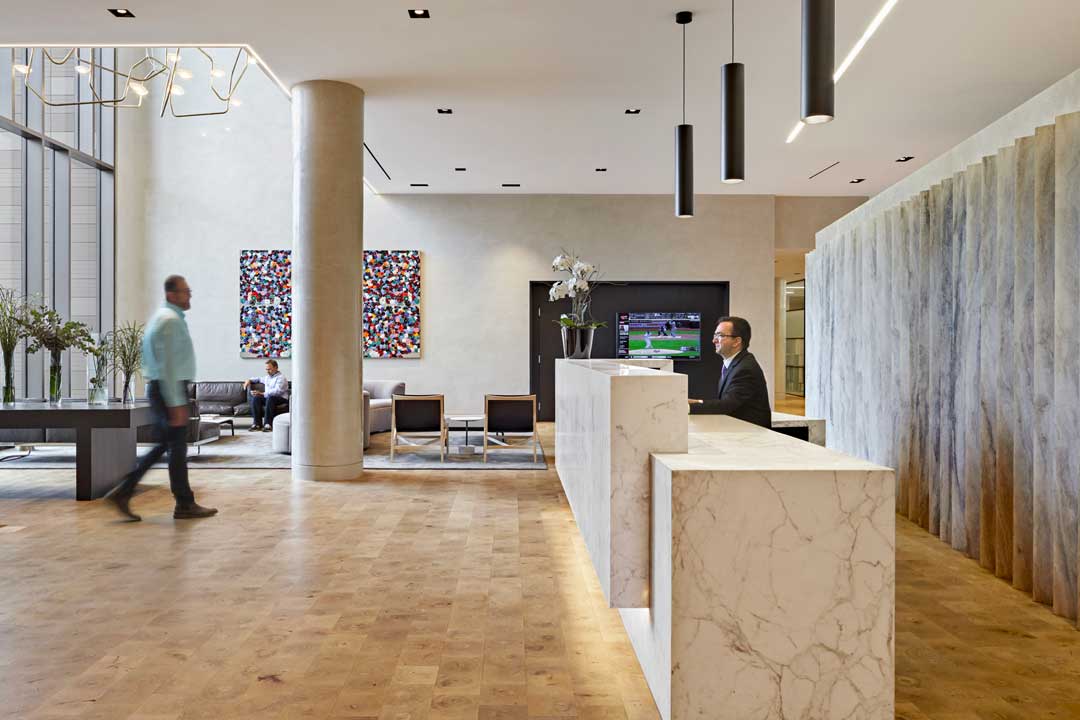 Open lobby with concierge desk, public sitting areas, and communal TV.
