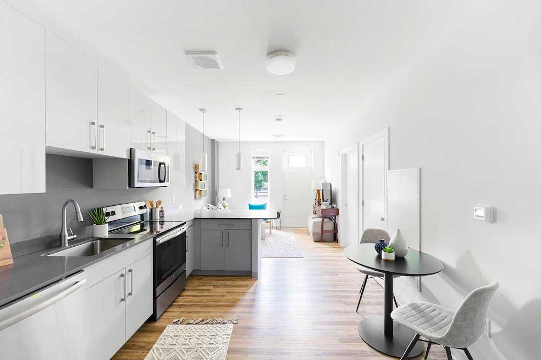 Apartment interior features modern kitchnen, designer finishes and flooring, large windows.