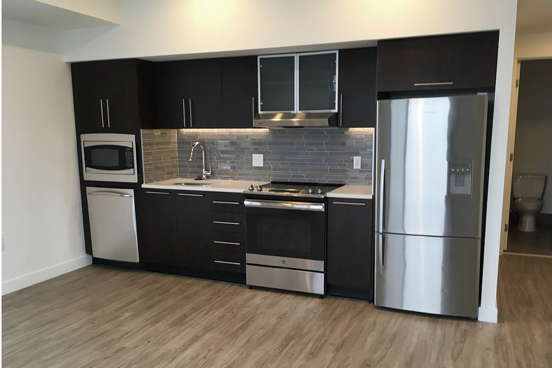 Modern steel appliances, designer black cabinetry, luxury flooring.