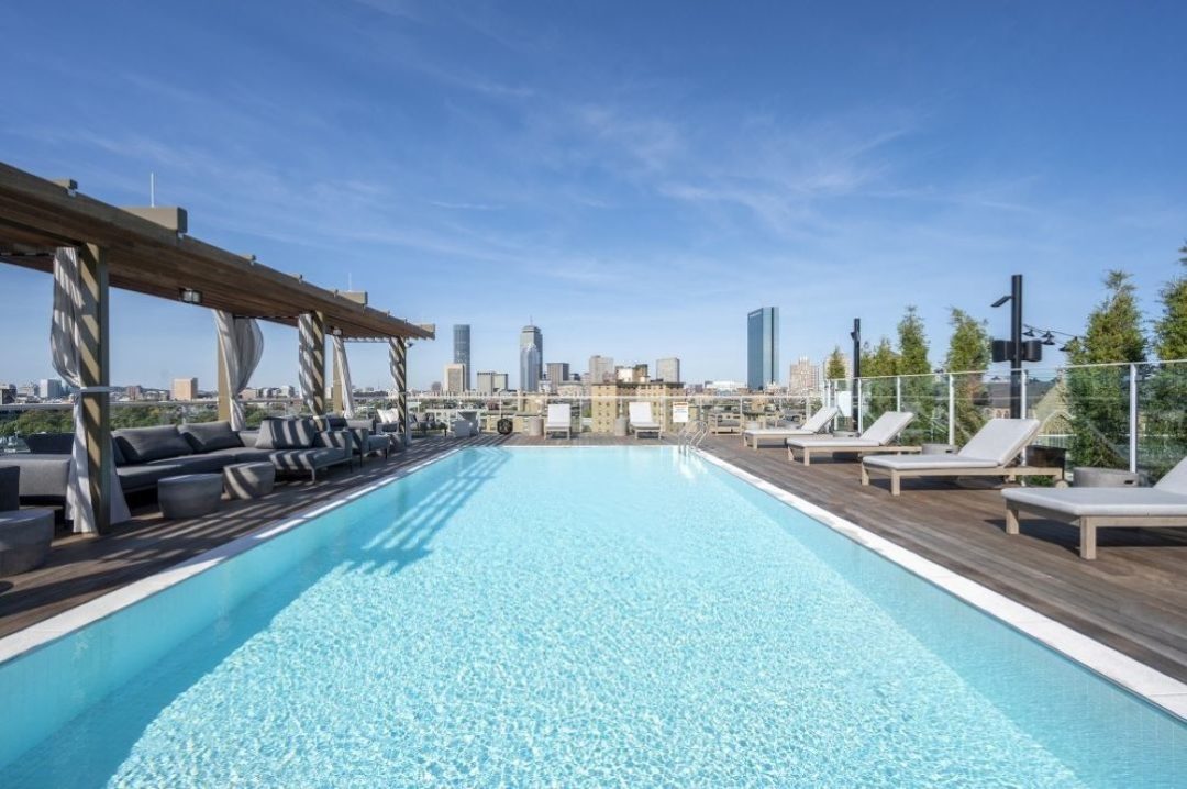 POV view of rooftop pool, pool deck, and cabanas with skyline views