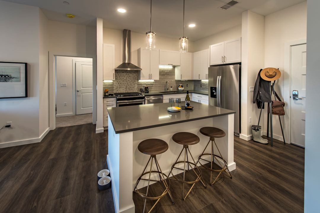 Open floor plan kitchen with high ceilings, grey countertops, big island, flat-top stove, oven, dishwasher, and refrigerator