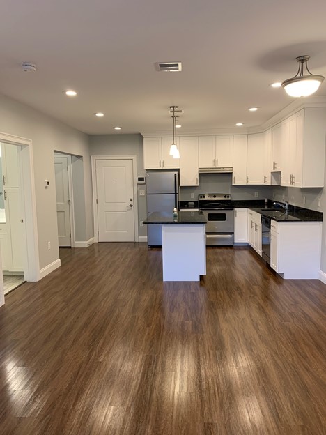 Open floor plan into modern kitchen with an island, beautiful flooring, modern feel.