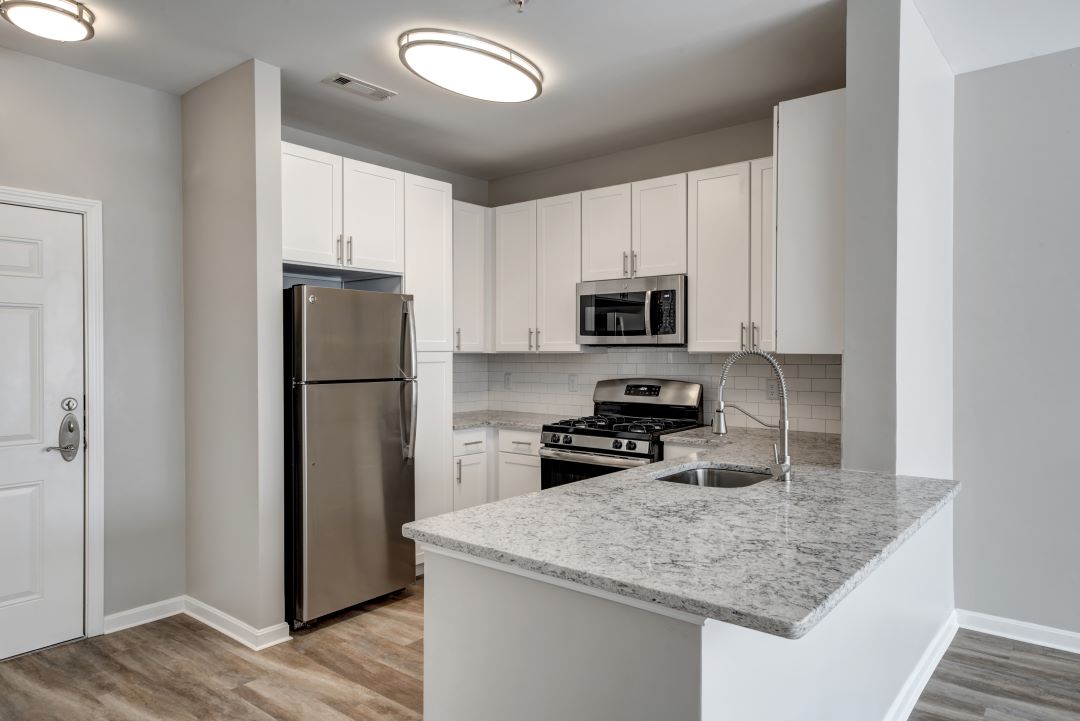 Kitchen with high ceilings, white cabinets, granite countertops, refrigerator, gas stove, oven, and microwave
