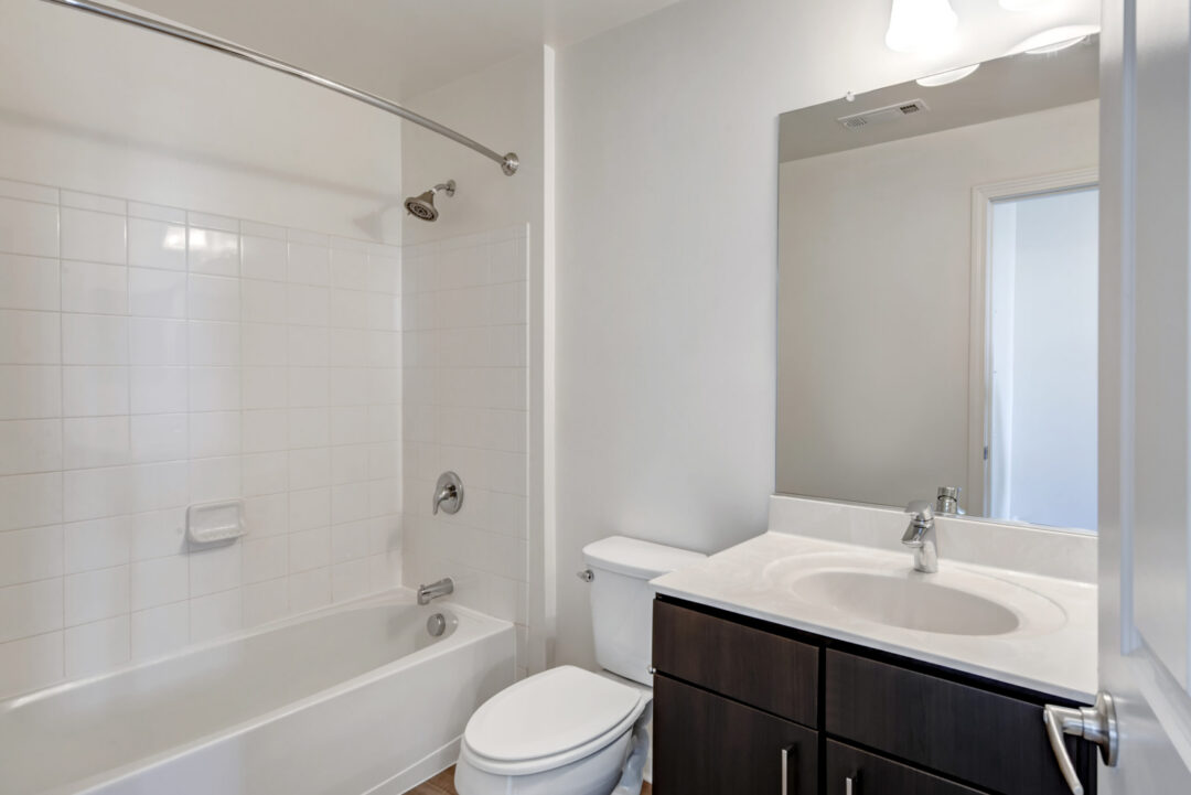 apartment style bathroom with an integrated tub-shower combo, dark wood cabinets