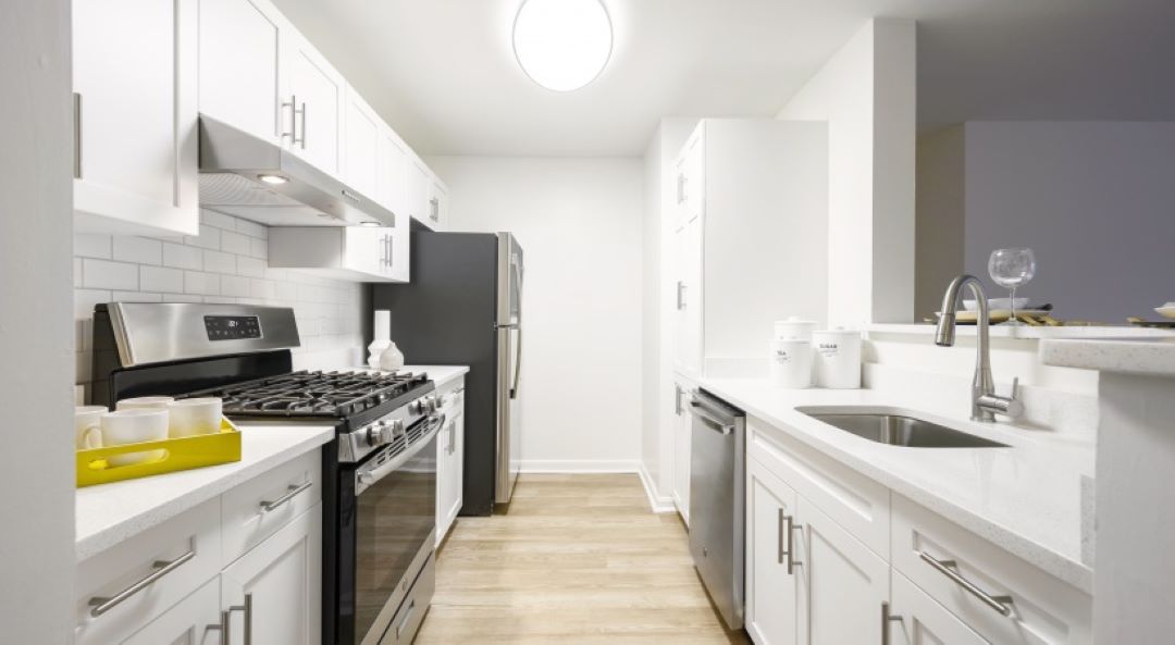 Kitchen with white cabinets and countertops, gas stove, oven, dishwasher, and refrigerator