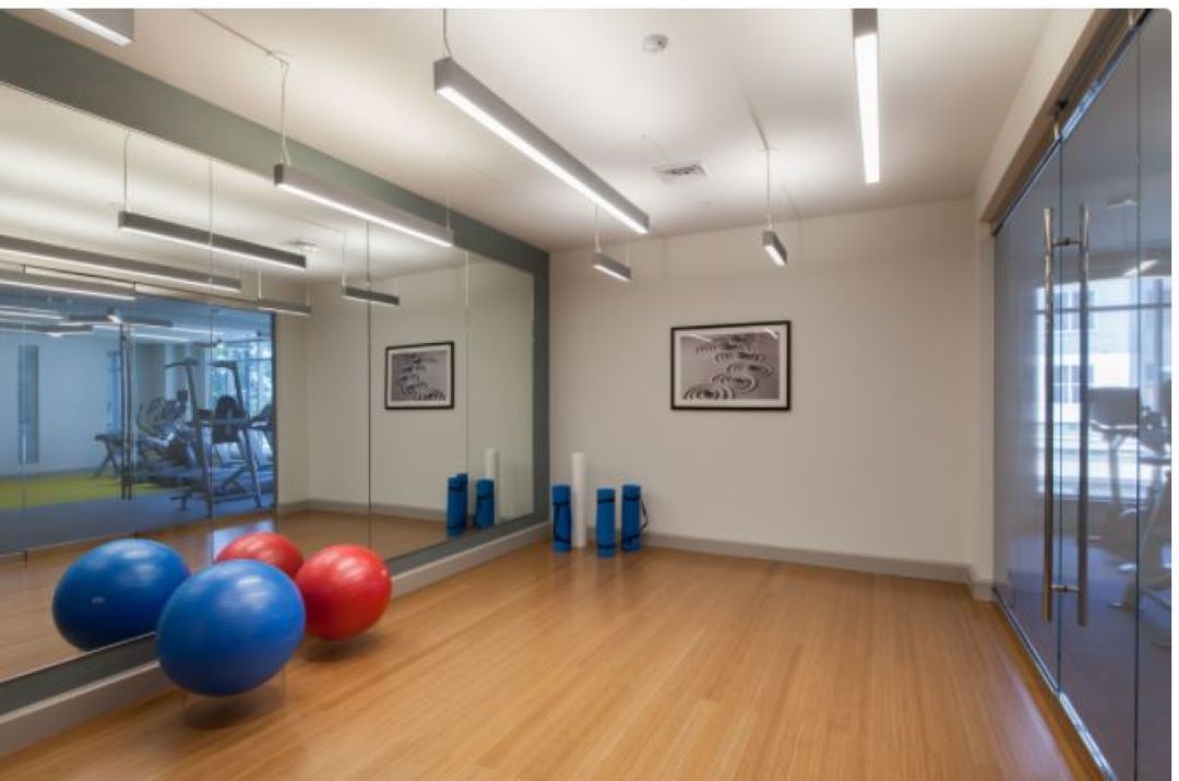 Hardwood yoga studio with mirrors inside the fitness center