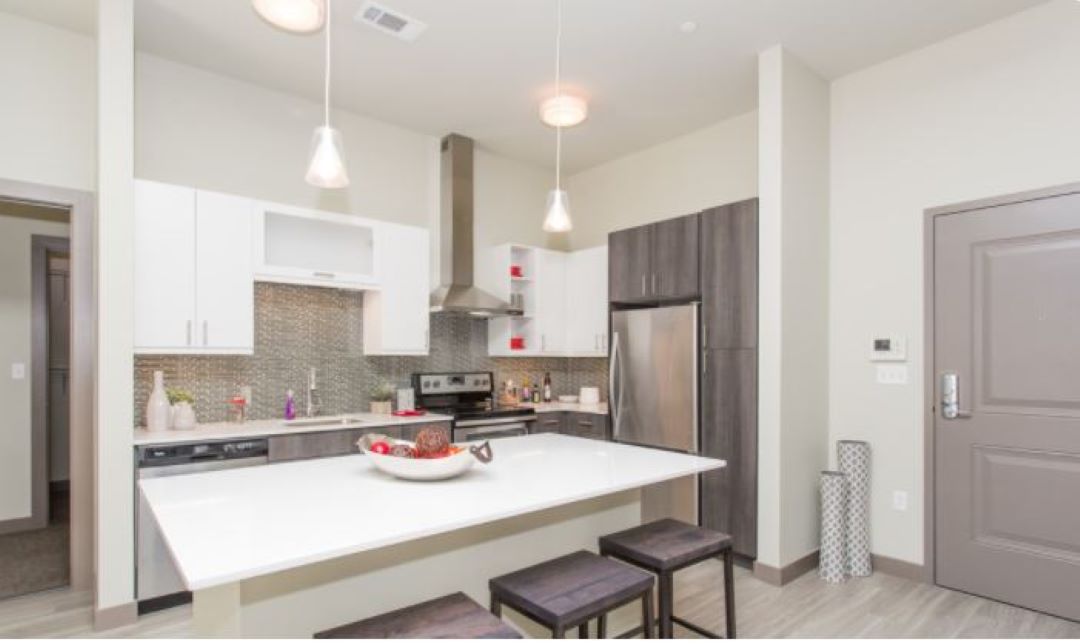 Open floor plan kitchen with white counters, loft ceilings, island, dishwasher, flat-top stove, oven, refrigerator