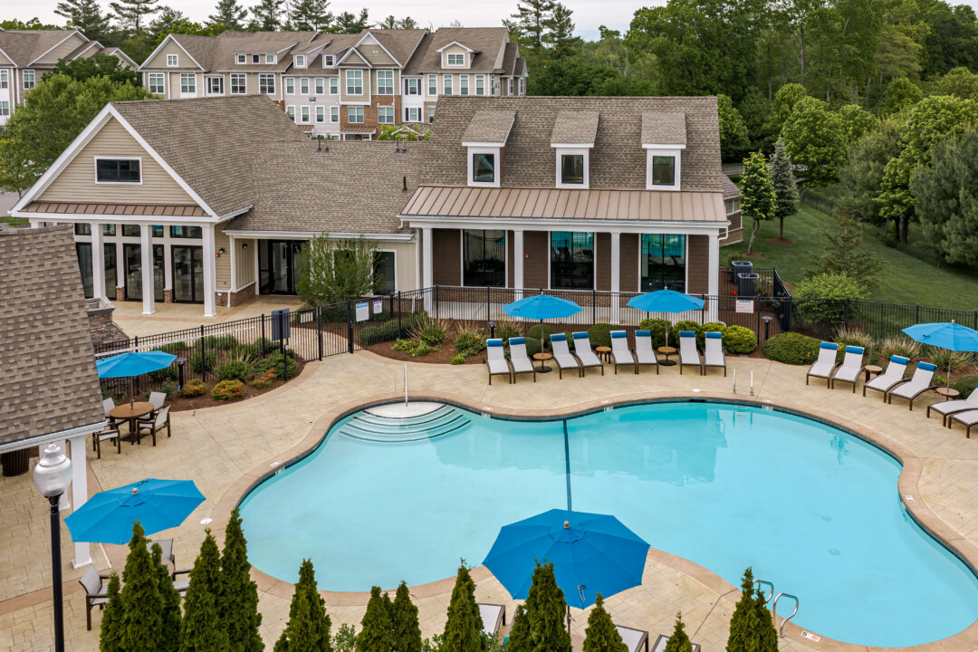 Aerial view of the community swimming pool, clubhouse, and landscaped outdoor amenities at Prynne Hills Apartments.