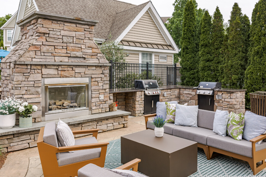 Poolside outdoor lounge with stone fireplace, grilling stations, and comfortable seating for residents and guests.