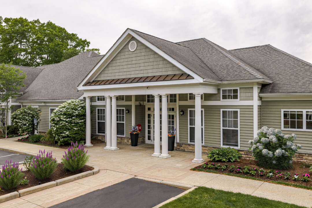 Elegant clubhouse entrance with covered portico, landscaped gardens, and welcoming community amenities at Prynne Hills Apartments.