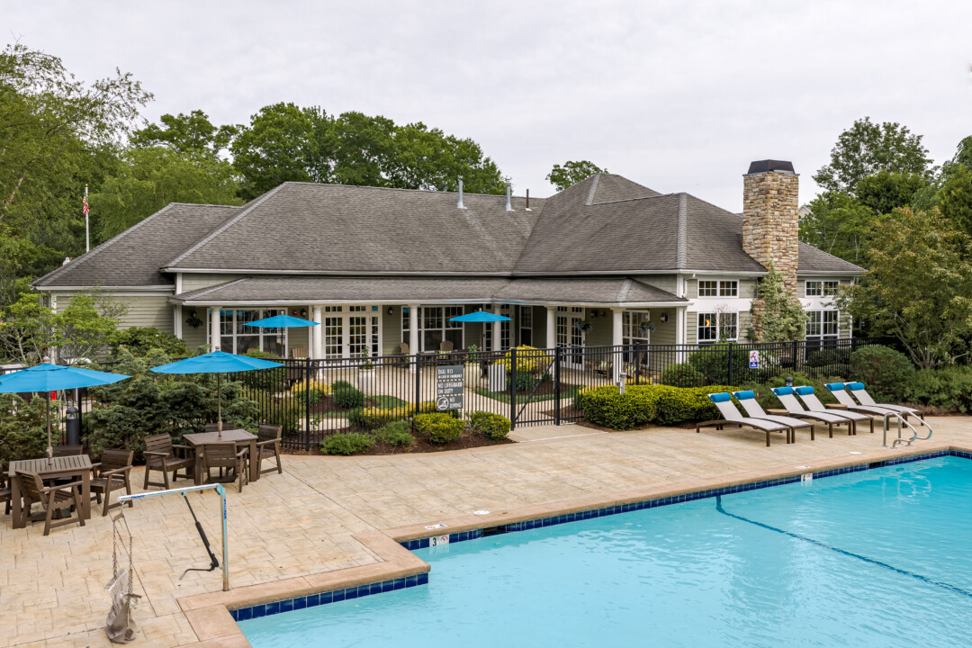 Community clubhouse overlooking the resort-style swimming pool with outdoor seating and landscaped grounds.