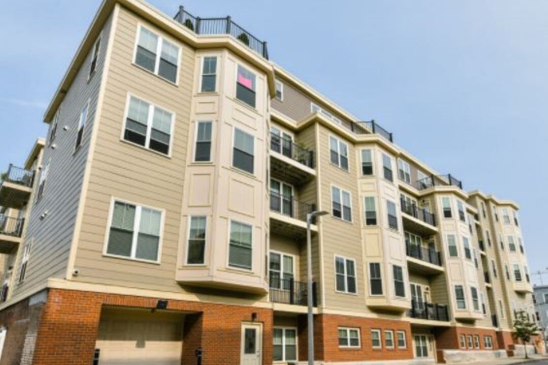 Street view of 4 story building with bay windows.