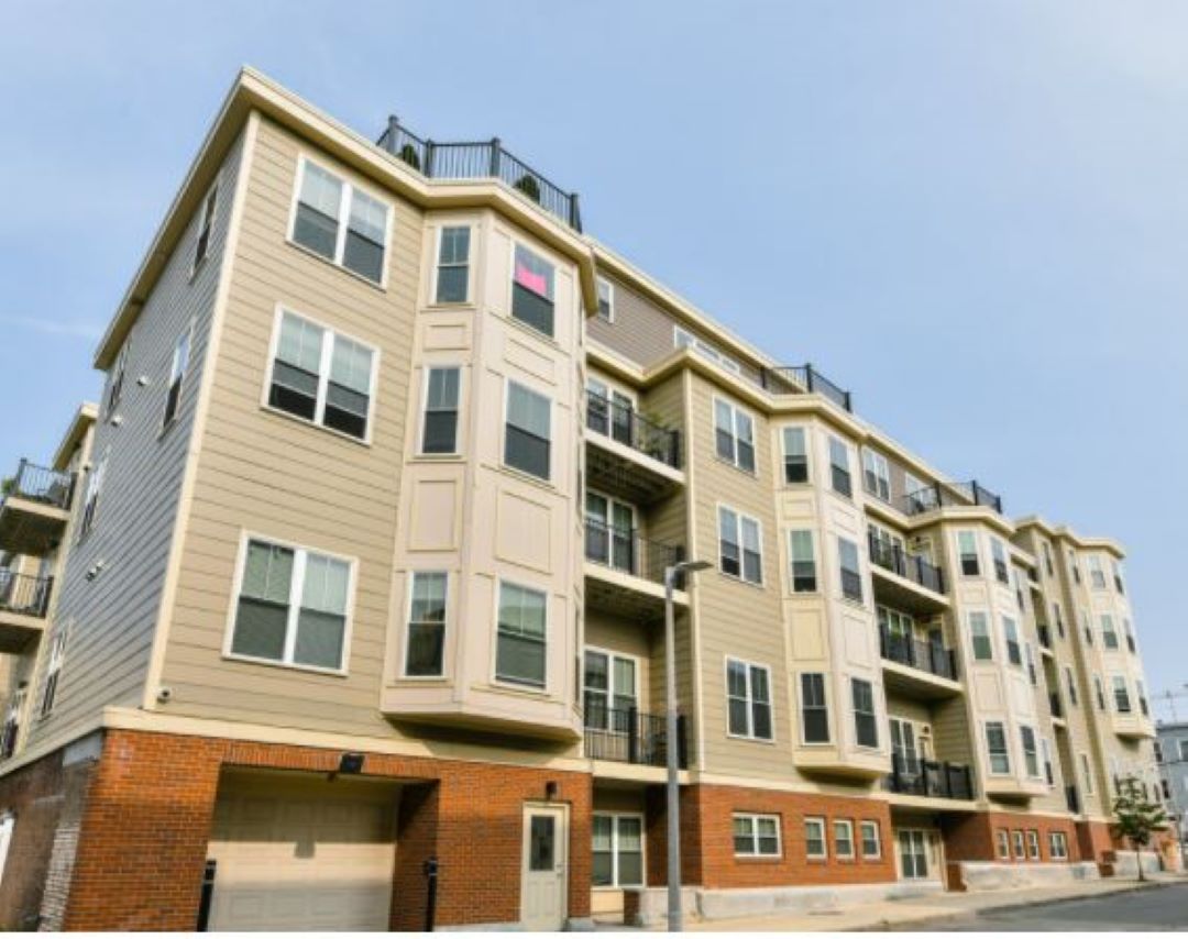 Street view of 4 story building with bay windows.