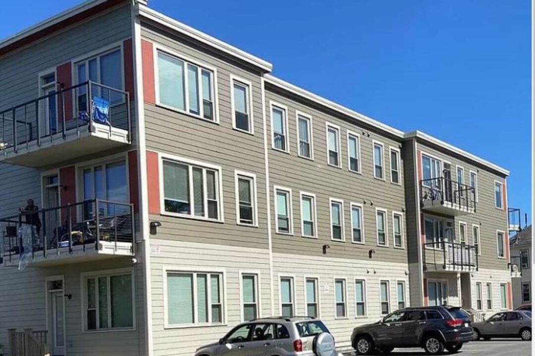 Three story building with parking and some balconies.