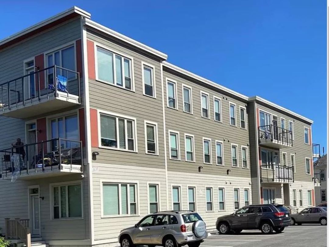 Three story building with parking and some balconies.