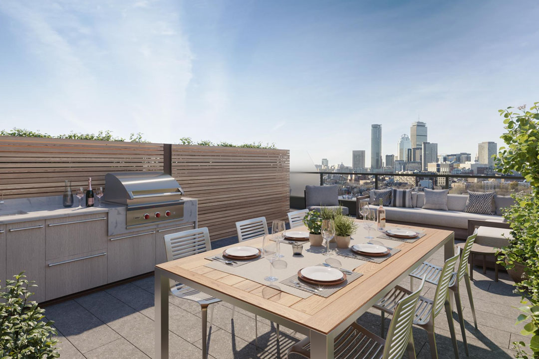 Skyline views of Boston (Prudential, etc) from roof deck dining area and lounge with grill, countertops, dining table, chairs and couches.