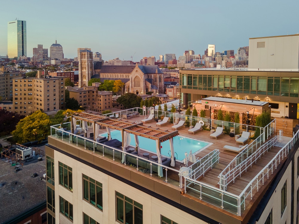 Pool and pool deck with lounge chairs, cabanas, and skyline views