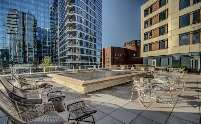 Rooftop patio with public seating areas, tables, water fountain, and skyline views