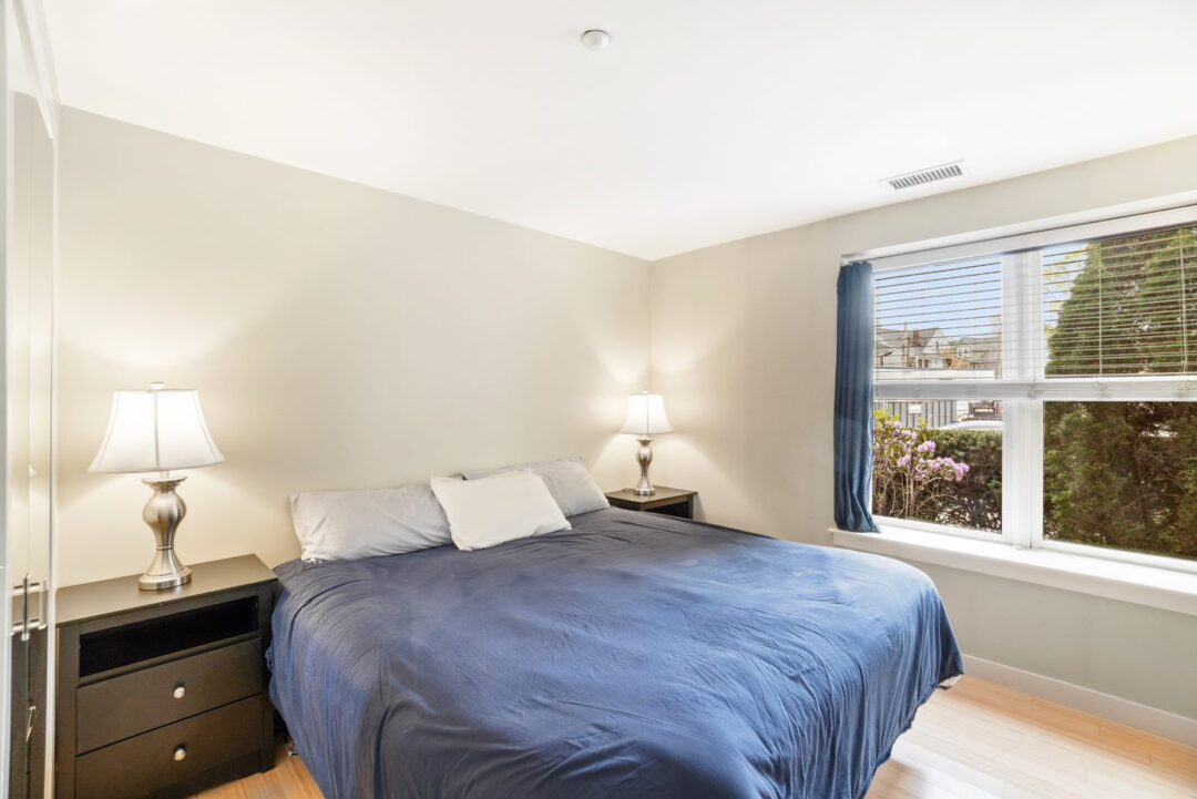 small beige bedroom with hard woods floors and picture window