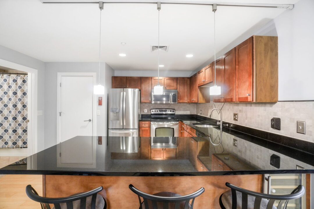 Modern kitchen with steel appliances, designer cabinetry and breakfast bar