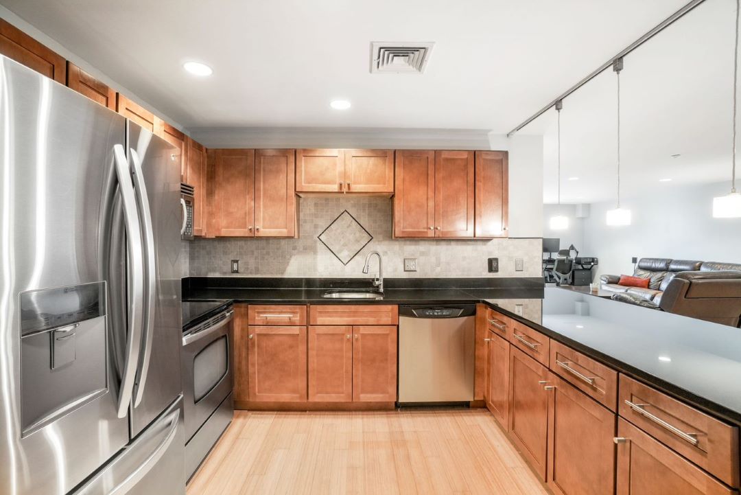Modern kitchen with steel appliances, designer cabinetry and hardwood flooring