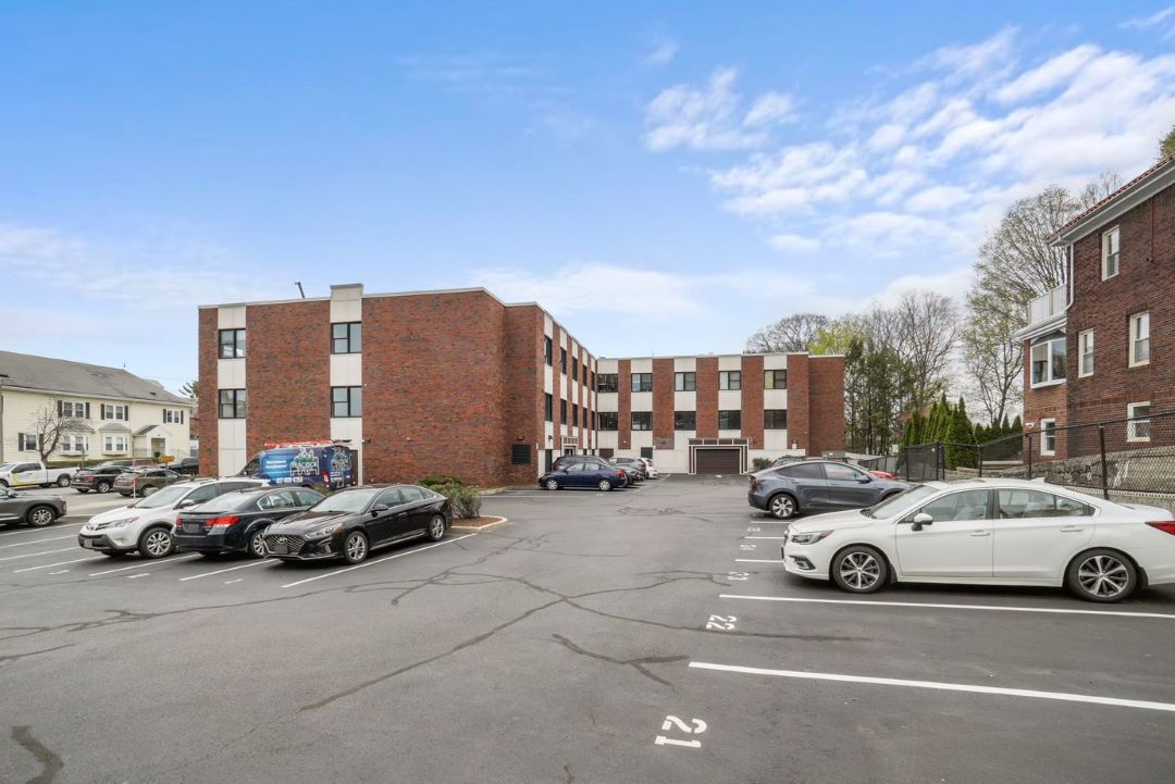 3 story condo style brick building rear view with parking spots