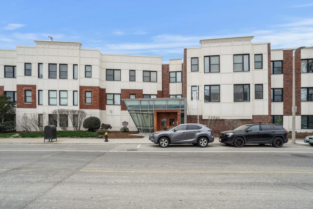 3 Story condo style building with brick and stone facade and lots of windows