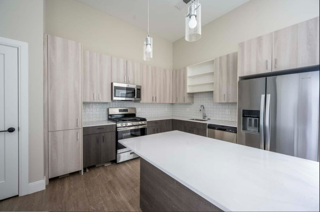 Kitchen with light and dark wood cabinets, microwave, flat top stove, oven, and refrigerator