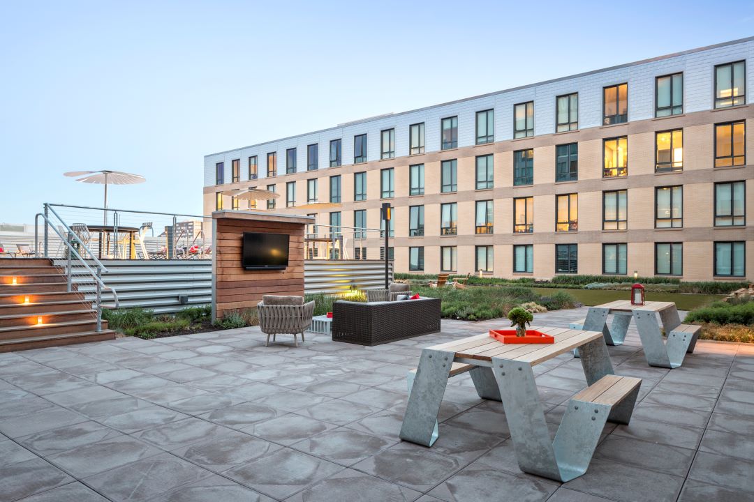 outdoor courtyard patio with picnic tables, couches and a tv