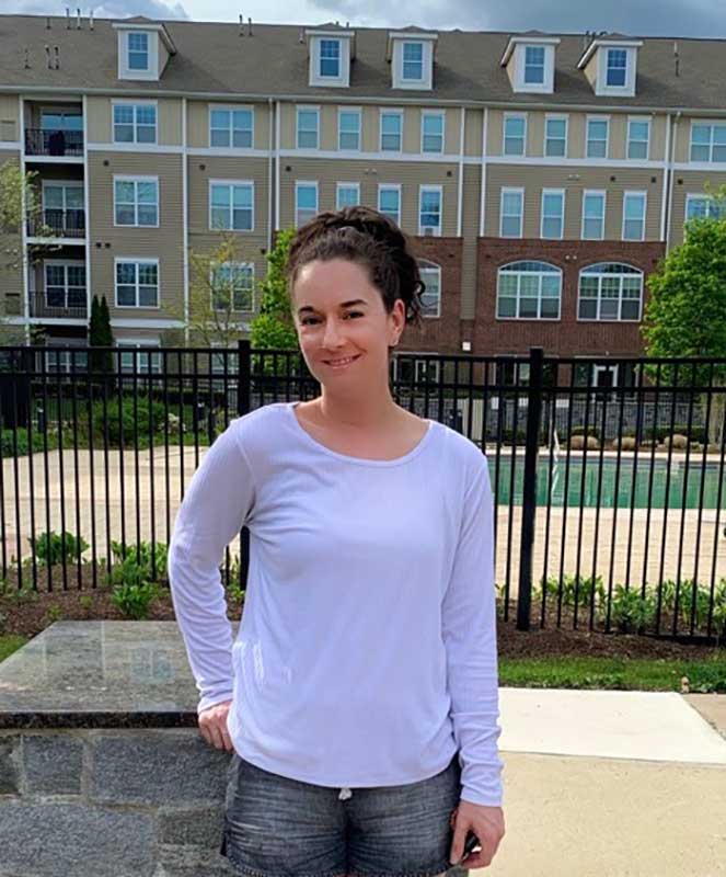 Young person standing in patio area with a pool.