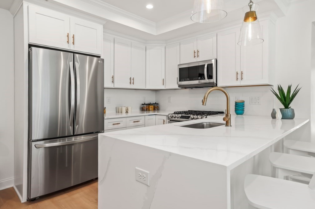 Kitchen with white cabinets and countertops, refrigerator, microwave, and stove/oven