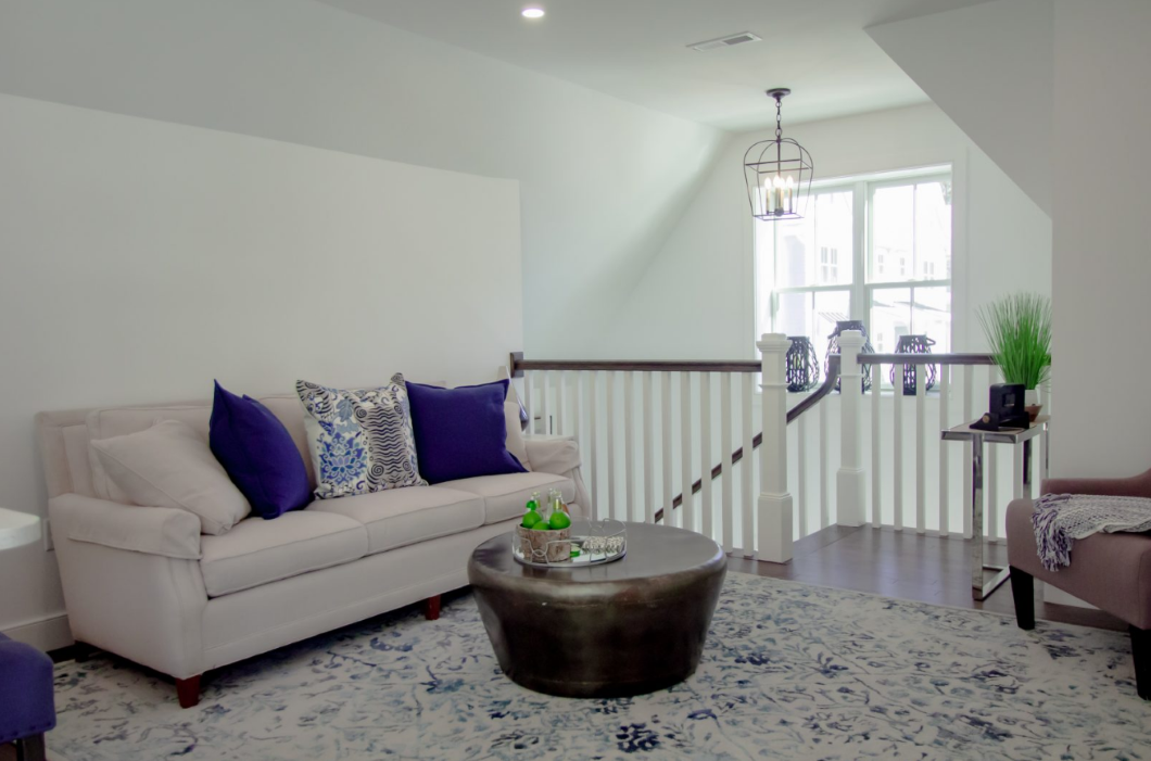 Living room with high ceilings and staircase to downstairs entrance.