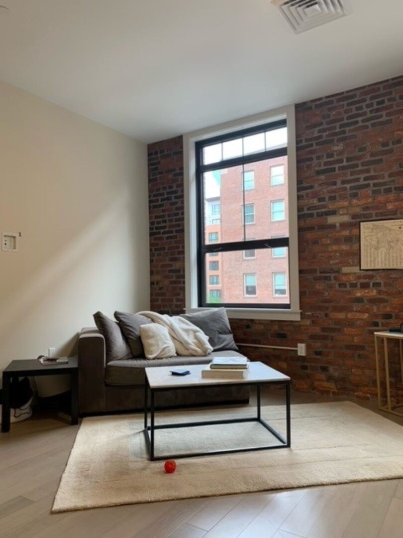 Open layout living room with big windows and brick wall
