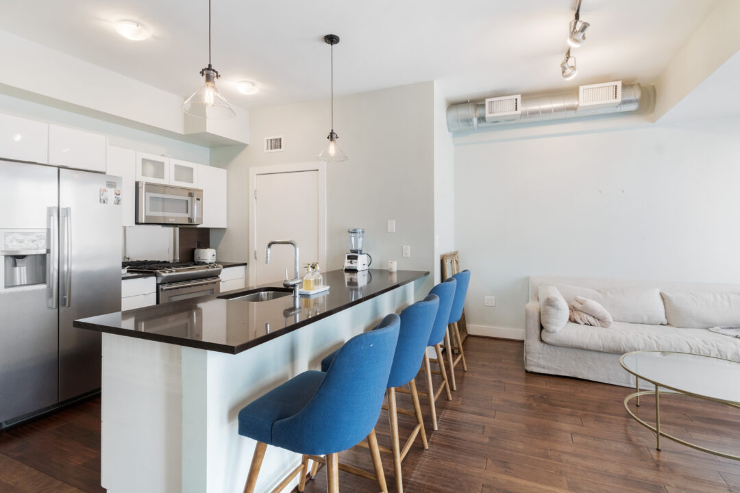 Modern kitchen with steel appliances, designer cabinetry and luxury plank flooring.