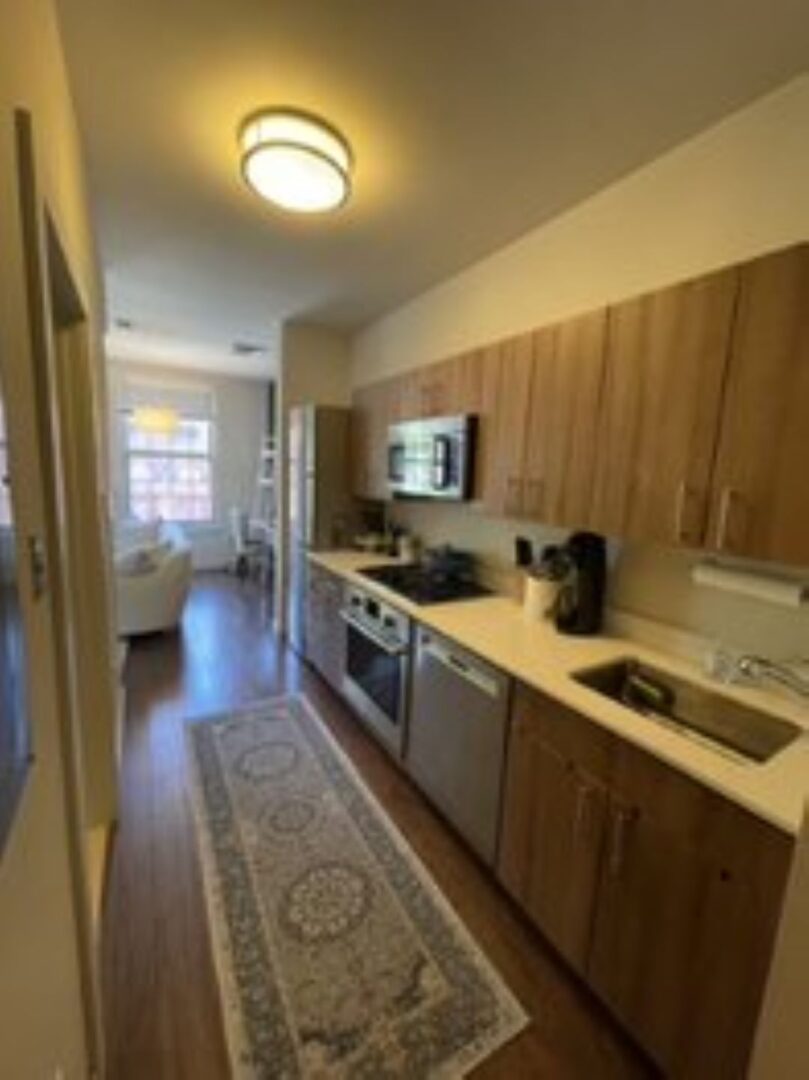 Modern kitchen with steel appliances, modern cabinets and hardwood flooring.