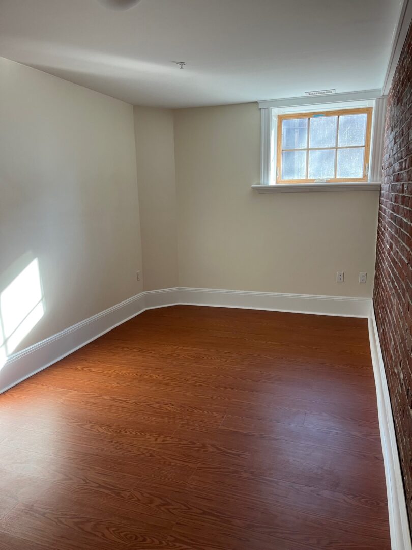 Bedroom with hardwood floors and brick wall