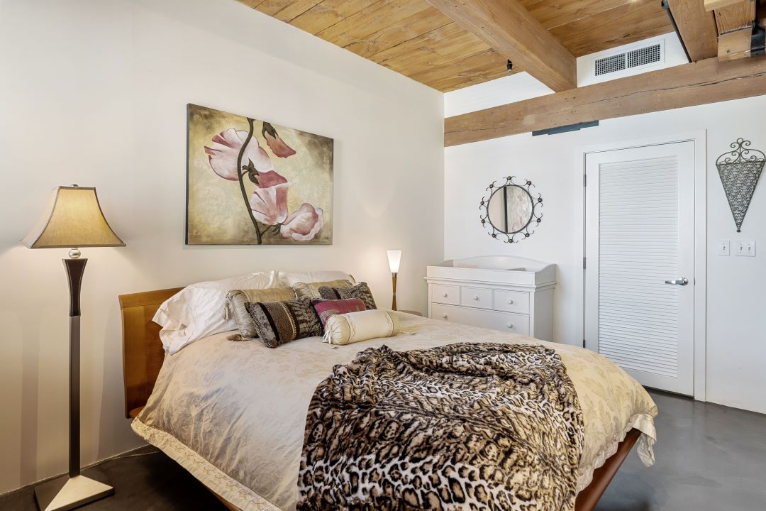 small beige bedroom with exposed wood ceilings