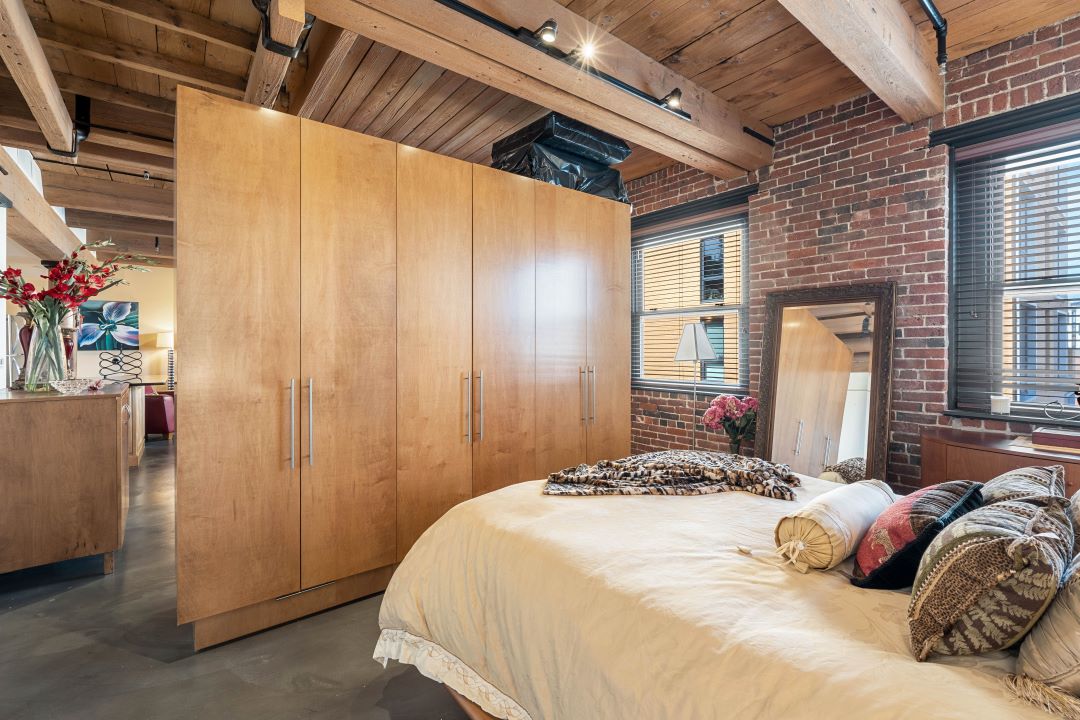 small beige bedroom with exposed wood ceilings and closet space