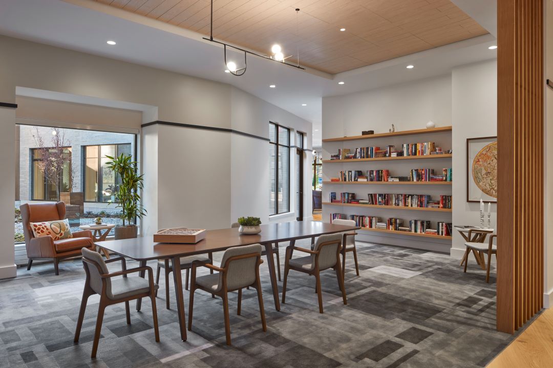 library area room with natural light, tables, chairs and a wall of books