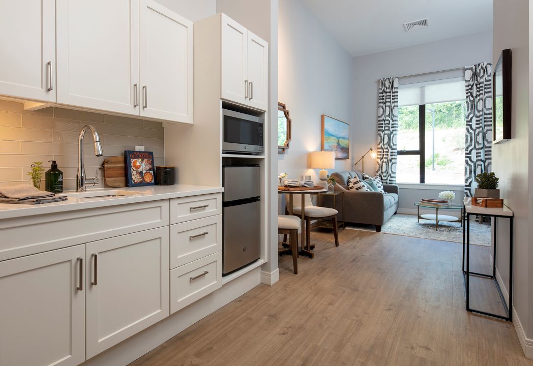 kitchen dining room area with updated appliances, white cabinets and hardwood floors