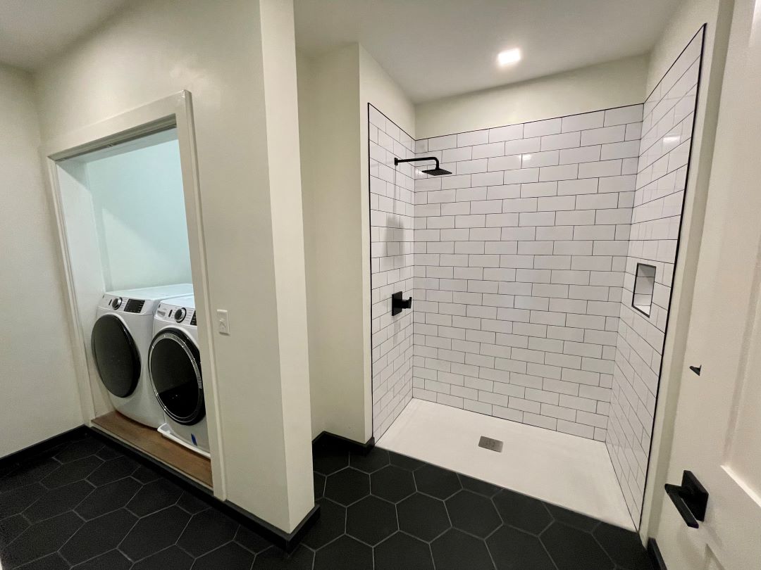 updated bathroom with modern shower and washer dryer in closet