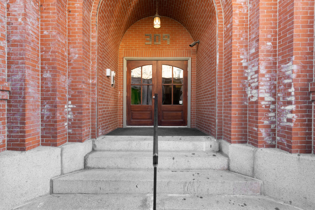 brick condo style building with stairs and double entry doors