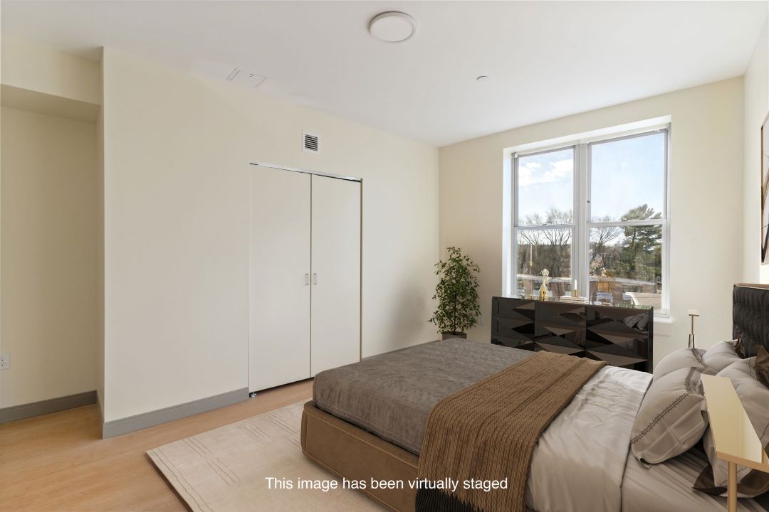 small beige bedroom with hardwood flooring, picture window and natural lighting