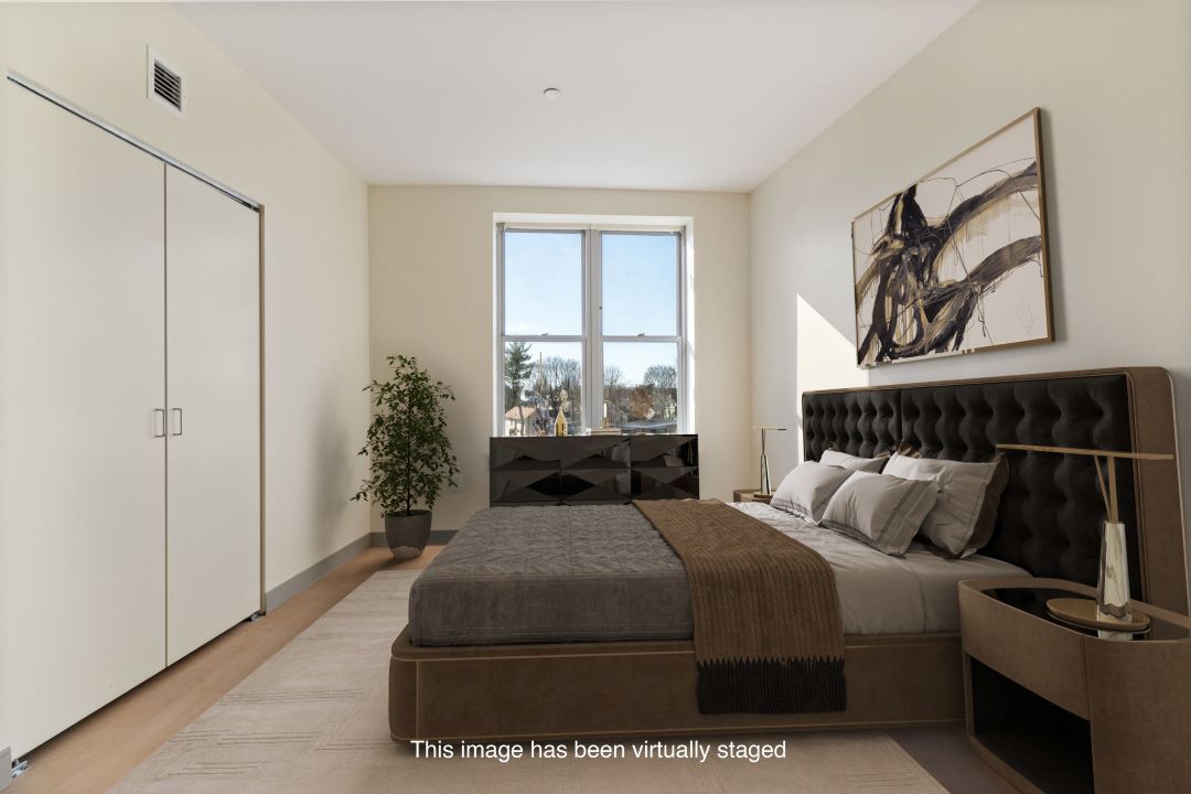 small beige bedroom with hardwood flooring, picture window and natural lighting