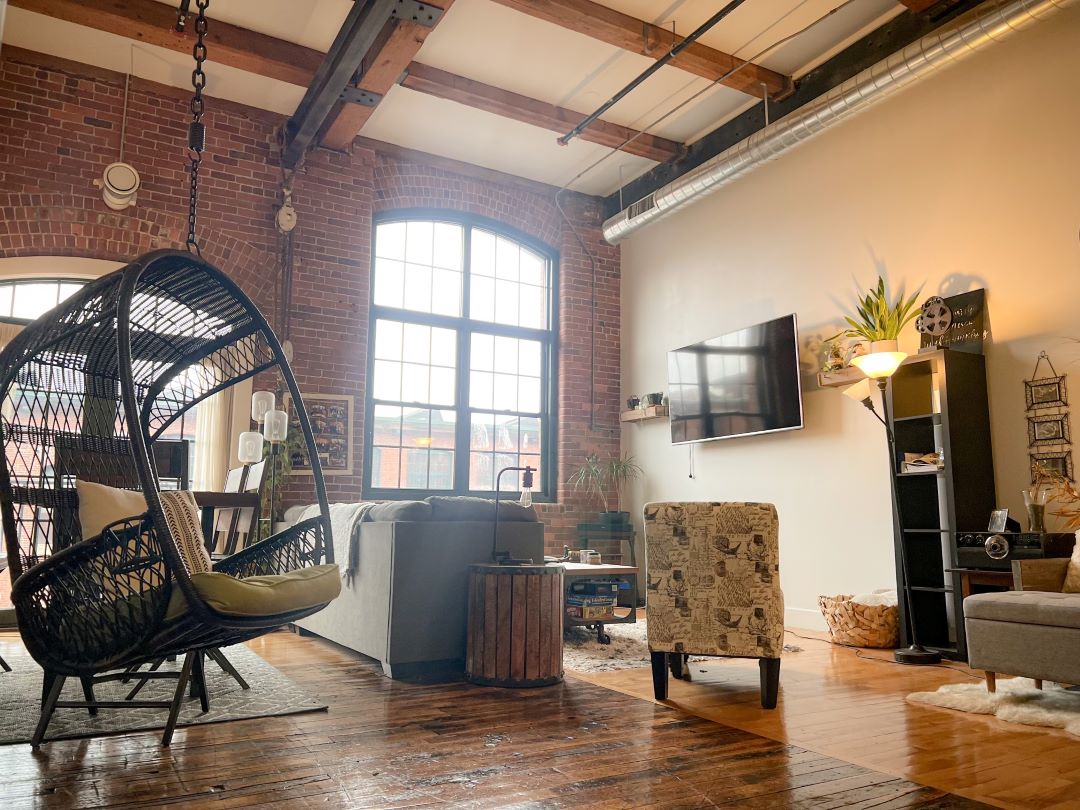 main living space with wood floors, brick walls, exposed beams/duck work and natural light