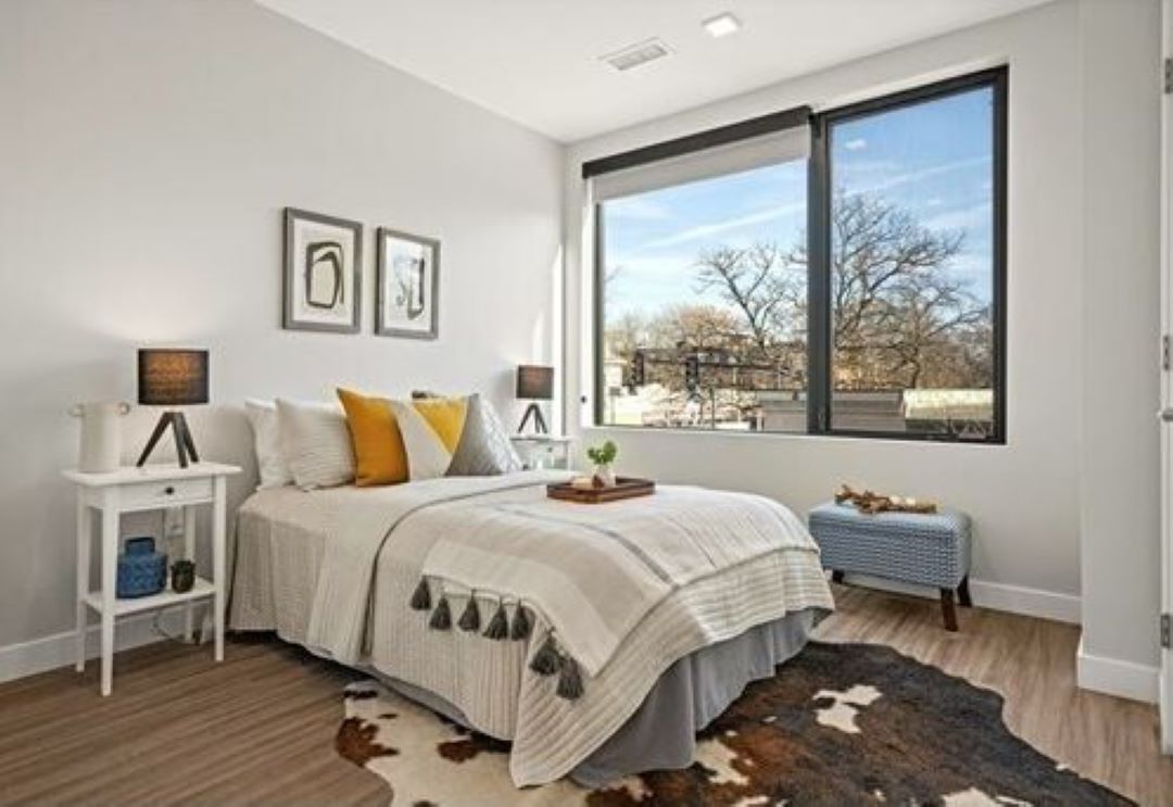 small beige bedroom with wood floors and large picture window