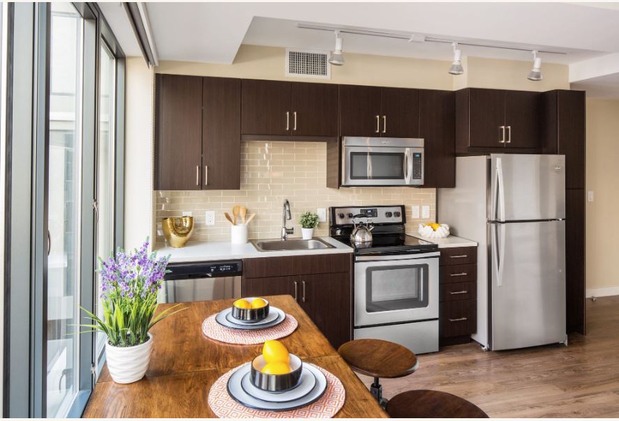modern kitchen with dark cabinets, stainless steel appliances and wood floors