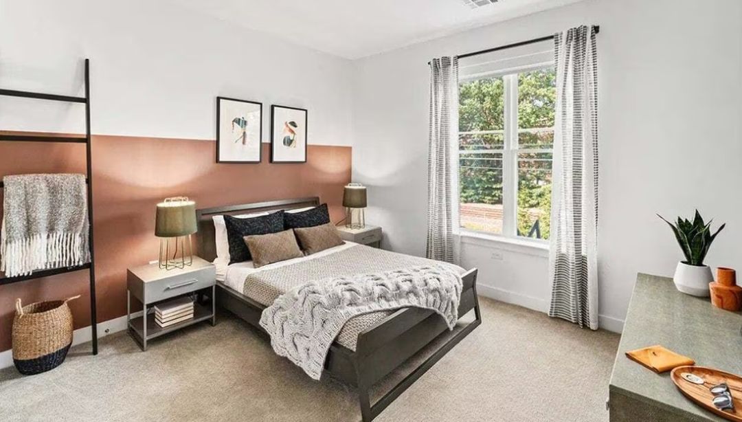 bedroom with beige and brown walls, carpet floors and large picture window