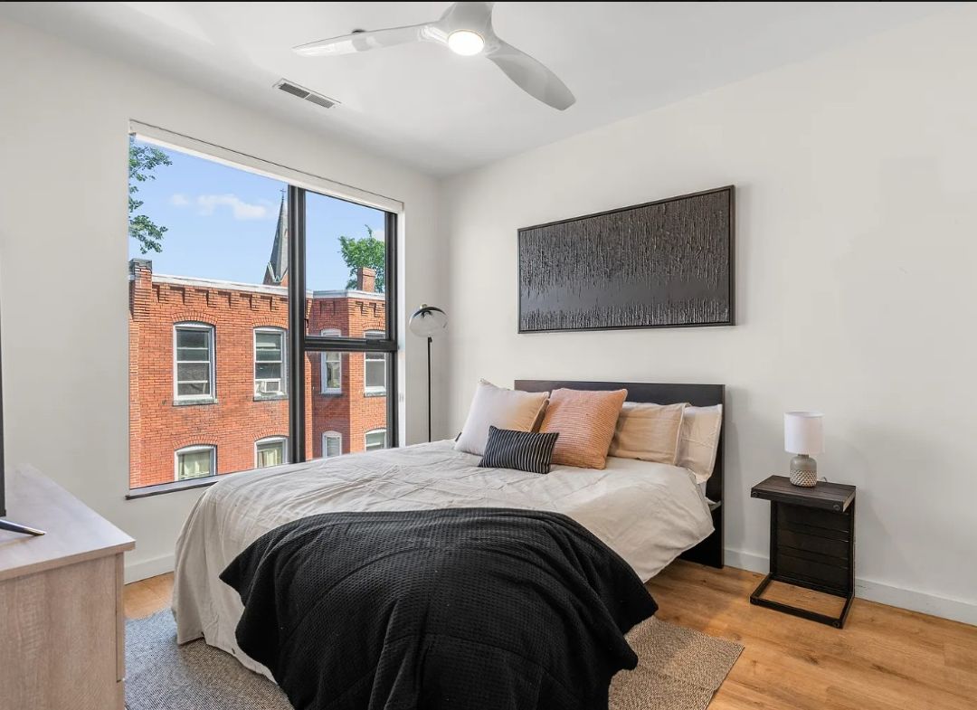 small bedroom with picture window, wood floors and ceiling fan